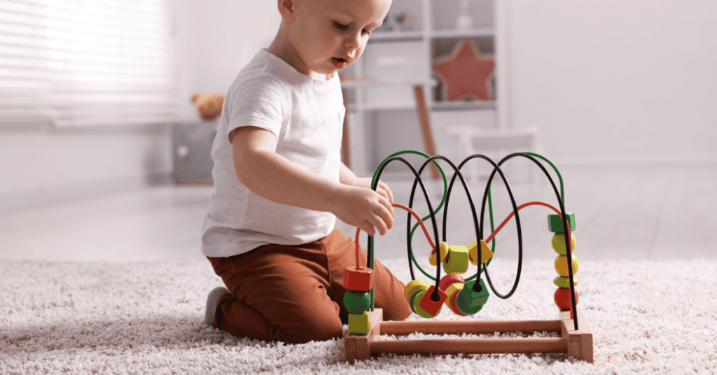 Niño jugando con juguete de desarrollo motor y caminos de bolas en interior.